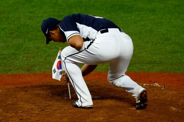 優勝してマウンドに韓国国旗を立てる韓国代表選手（写真：ロイター/アフロ）