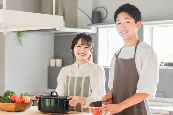 一緒に料理を作る若い夫婦（写真はイメージ）
