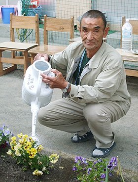 花が趣味の三浦さん。避難所の花壇の水やりが日課になっている＝大槌町の安渡小学校避難所で