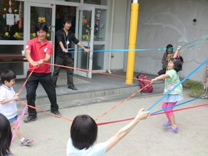 色とりどりのゴムバンドを使って遊ぶ子どもたち。左奥は難民を助ける会の小菅健太郎