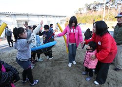 「一緒に乗ろうよ！」上級生の子どもたちが、小さな子にも声をかけていました。右は東京事務局の宮崎佐和子（2012年3月14日、福島県相馬市）