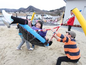 子どもたち3~4人が一緒に乗れるゆりかごスウィング。上級生や大人に大きく揺らしてもらって遊びます（2012年4月13日、福島県相馬市）