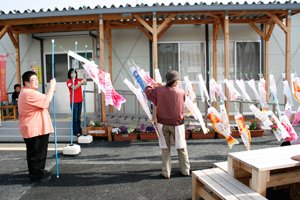 イベント終了後、仮設住宅にお住まいの皆さまのご協力の下、集会所の前にこいのぼりを設置しました（左端は東京事務局の浅野武治。2012年4月29日）