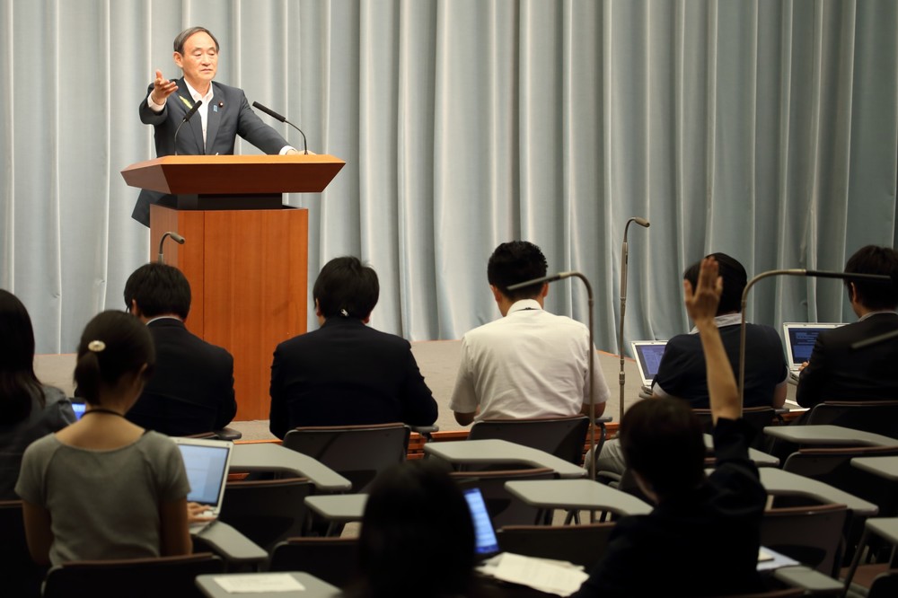 東京新聞・望月記者（手前）を指名する菅義偉官房長官（奥）