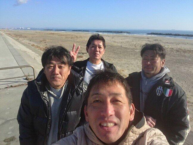 Hiroshi Maenohama (front center) and Kaoru Suenaga (behind center) taking photos with friends after surfing = Provided by Maenohama on the Arahama coast in December 2019