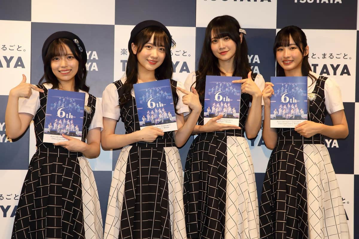 書籍を手にするメンバー4人。8月28日に発売される