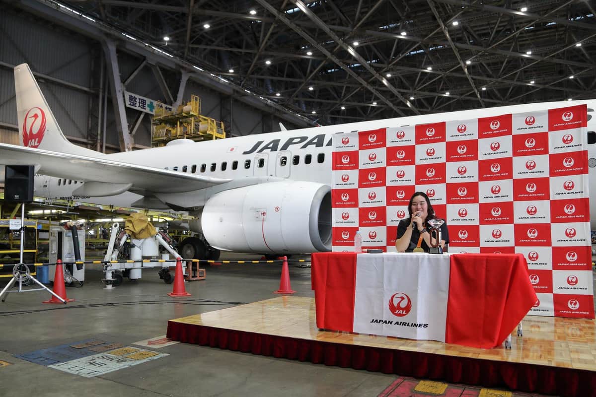 記者会見は羽田空港内の格納庫で開かれた