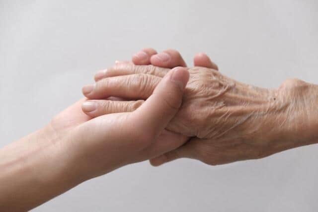 高齢者の手を握る若者